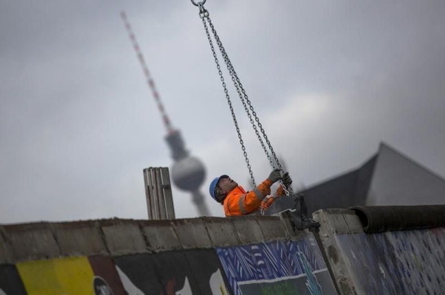 Un ouvrier attache un morceau du mur à une grue devant les manifestants, 1er mars 2013 - @Thomas Peter pour Reuters