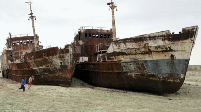 Children run past ruined ships abandoned in sand that once formed the bed of the Aral Sea. Lake Balkhash in Kazakhstan faces the danger of becoming another Aral Sea because of upstream diversion by China. Crédits photo — Reuters