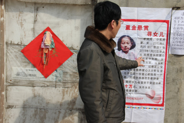 Un homme devant le poster signalant le rapt d'un enfant Un homme devant le poster signalant le rapt d'un enfant