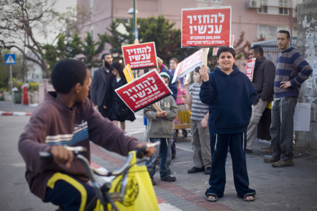 Des habitants de Tel-Aviv brandissent des pancartes « Retournez chez vous » en direction d'un jeune garçon noir. Crédit Photo -- Oren Ziv / ActiveStills