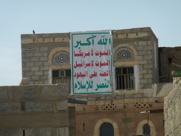 Maison à Dhamar, sud-ouest du Yémen, arborant en septembre 2013 l'emblème des Houthis : « Dieu est grand / Mort à l'Amérique / Mort à Israël / Malheur sur les juifs / Victoire à l'islam ». Crédit : Abdullah Sarhan (licence CC BY-SA 4.0)